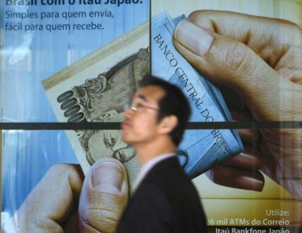 A man walks past a poster of a bank at a business district in Tokyo