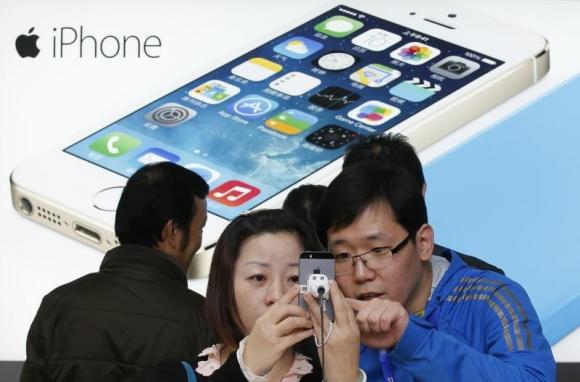 A staff of a China Mobile shop (R) explains a function of the iPhone 5s to a customer in Beijing