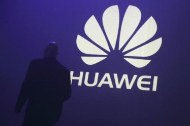 A man walks past a logo during the presentation the Huawei's new smartphone, the Ascend P7, launched by China's Huawei Technologies in Paris, May 7, 2014.  REUTERS/Philippe Wojazer