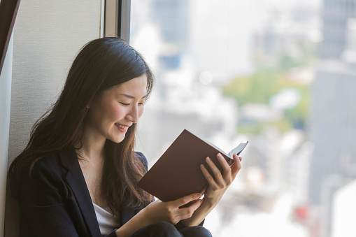 Young modern Japanese woman sitting reading a book
