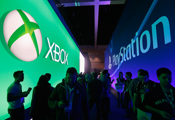 LOS ANGELES, CA - JUNE 16: Game enthusiasts and industry personnel walk between the Microsoft XBox and the Sony PlayStation exhibits at the Annual Gaming Industry Conference E3 at the Los Angeles Convention Center on June 16, 2015 in Los Angeles, California. The Los Angeles Convention Center will be hosting the annual Electronic Entertainment Expo (E3) which focuses on gaming systems and interactive entertainment, featuring introductions to new products and technologies. (Photo by Christian Petersen/Getty Images)