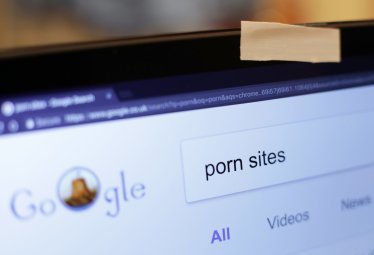 A piece of tape covering a laptop's webcam, with a porn search typed into the Google Chrome internet browser, in London