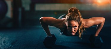 Cross training fitness. Young woman doing pushups with dumbbells. Panoramic image, convenient copy space