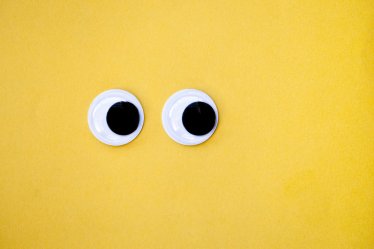 Googly eyes on a yellow background, looking sideways.