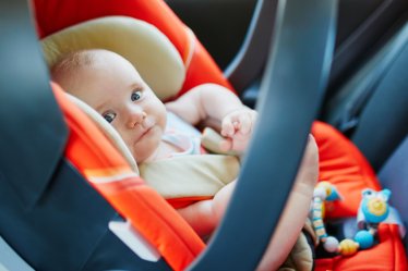 Adorable baby girl in modern car seat. Little kid traveling by car. Child safety on the road. Trip with an infant.