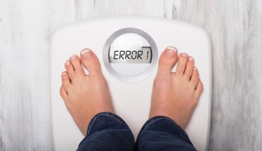Woman standing on weight scale showing error message