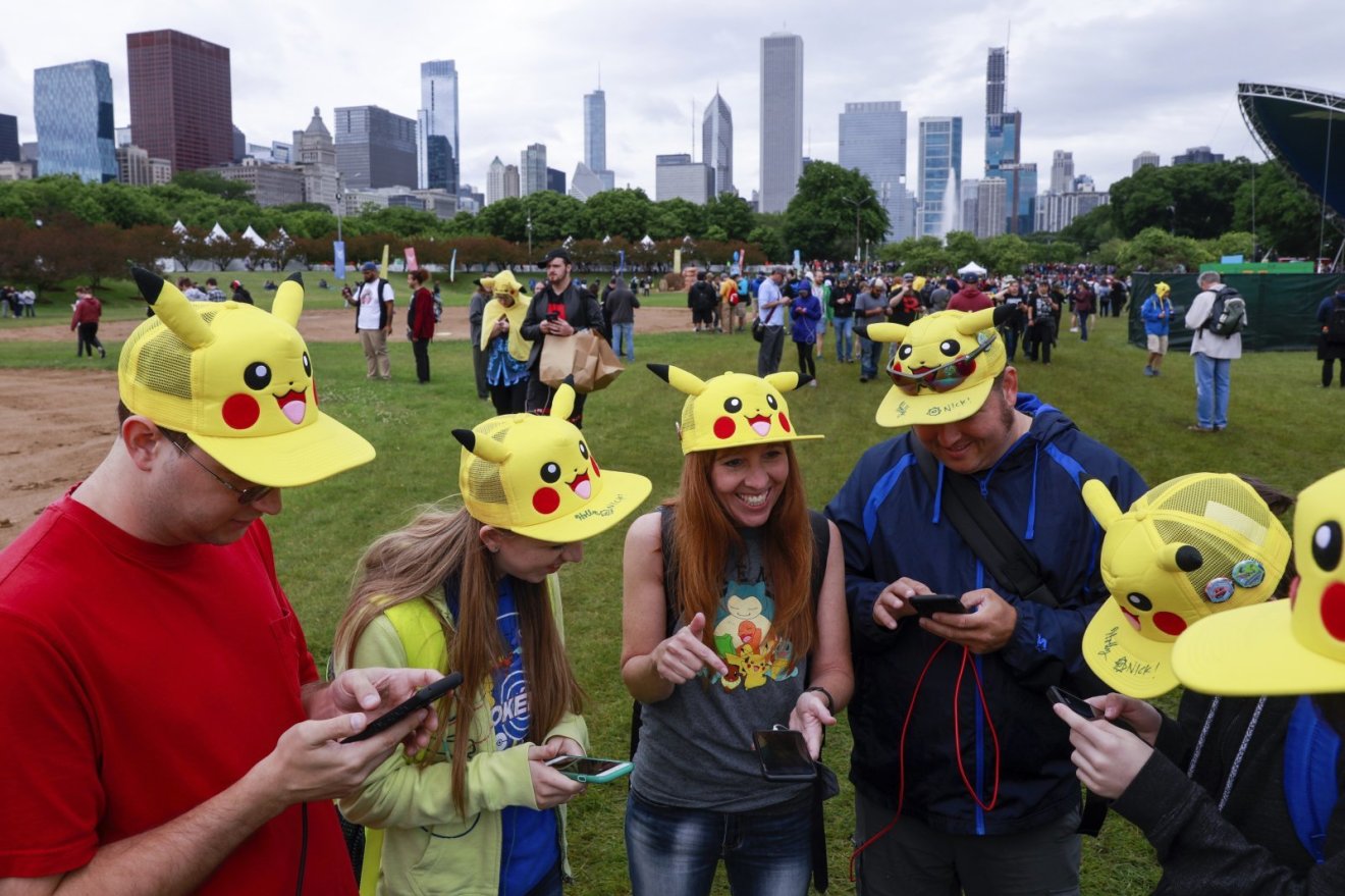 Tina Kellock, center, of Phoenix, Arizona, smiles with family and friends as they participate at the Pokemon GO Fest 2019 in Chicago's Grant Park Thursday, June 13, 2019. (AP Photo/Amr Alfiky)