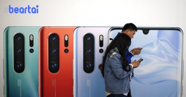 A Chinese couple browse their smartphones as they walk by the new Huawei P30 smartphone advertisement on display inside a subway station in Beijing, Monday, May 13, 2019. China's intensified tariff war with the Trump administration is threatening Beijing's ambition to transform itself into the dominant player in global technology. (AP Photo/Andy Wong)