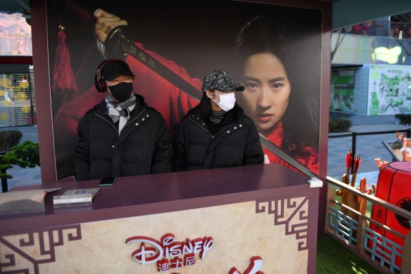 ภาพเคาน์เตอร์ขายตั๋ว Mulan ในจีนซึ่งยังคงขึ้นแบนเนอร์ฉายตามเดิม ขณะที่พนักงานสวมหน้ากากอนามัย (ภาพจาก nbcnews.com)