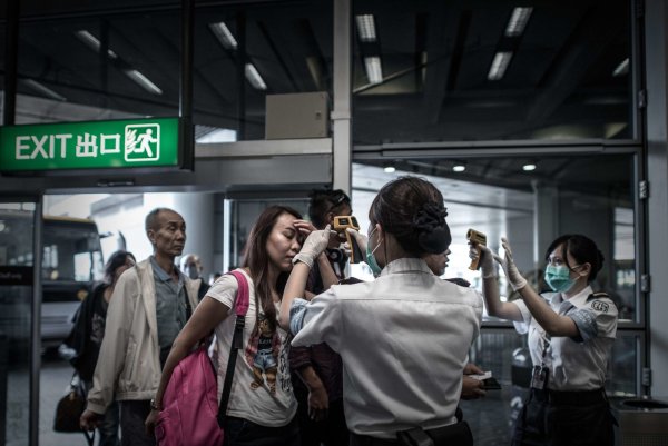 เจ้าหน้าที่วัดอุณหภูมิของกลุ่มผู็โดยสารในช่วงที่มีการแพร่ระบาดของโรคเมอร์ส ในสนามบินแห่งชาติฮ่องกง ปี 2015