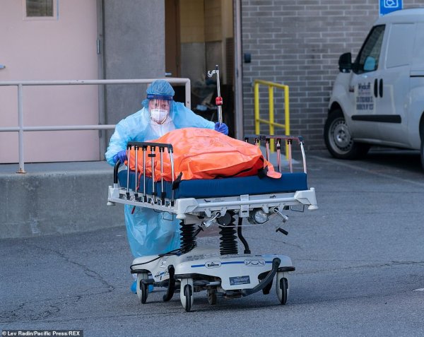 เจ้าหน้าที่เข็นร่างผู้เสียชีวิตที่บรรจุในถุงสีส้มออกมายังตู้คอนเทนเนอร์เก็บศพชั่วคราวนอกโรงพยาบาล