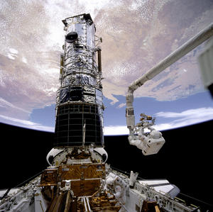 นักบินอวกาศกำลังซ่อมแซมระบบทัศนวิสัยของกล้องโทรทรรศน์อวกาศฮับเบิล ในภารกิจ STS-61   