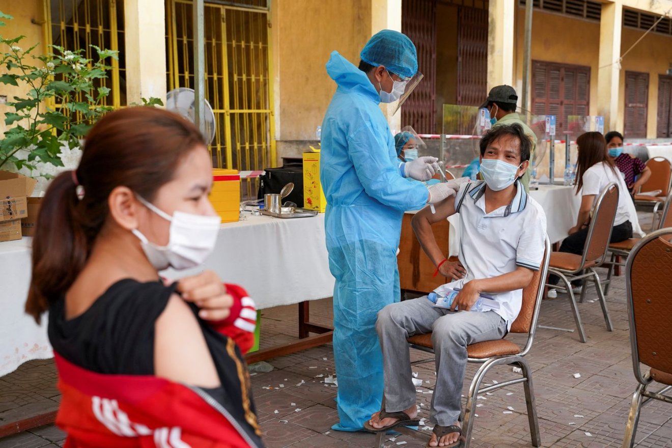 FILE PHOTO: A Cambodian army member vaccinates a person inside a red zone with strict lockdown measures, amidst the latest outbreak of the coronavirus disease (COVID-19), in Phnom Penh, Cambodia, May 1, 2021. REUTERS/Cindy Liu/File Photo