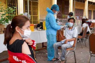 FILE PHOTO: A Cambodian army member vaccinates a person inside a red zone with strict lockdown measures, amidst the latest outbreak of the coronavirus disease (COVID-19), in Phnom Penh, Cambodia, May 1, 2021. REUTERS/Cindy Liu/File Photo