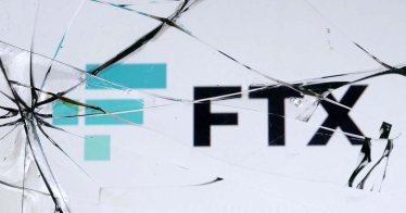 An FTX logo is seen through broken glass